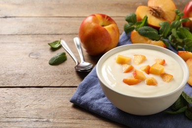 Delicious yogurt with fresh peach on wooden table, space for text