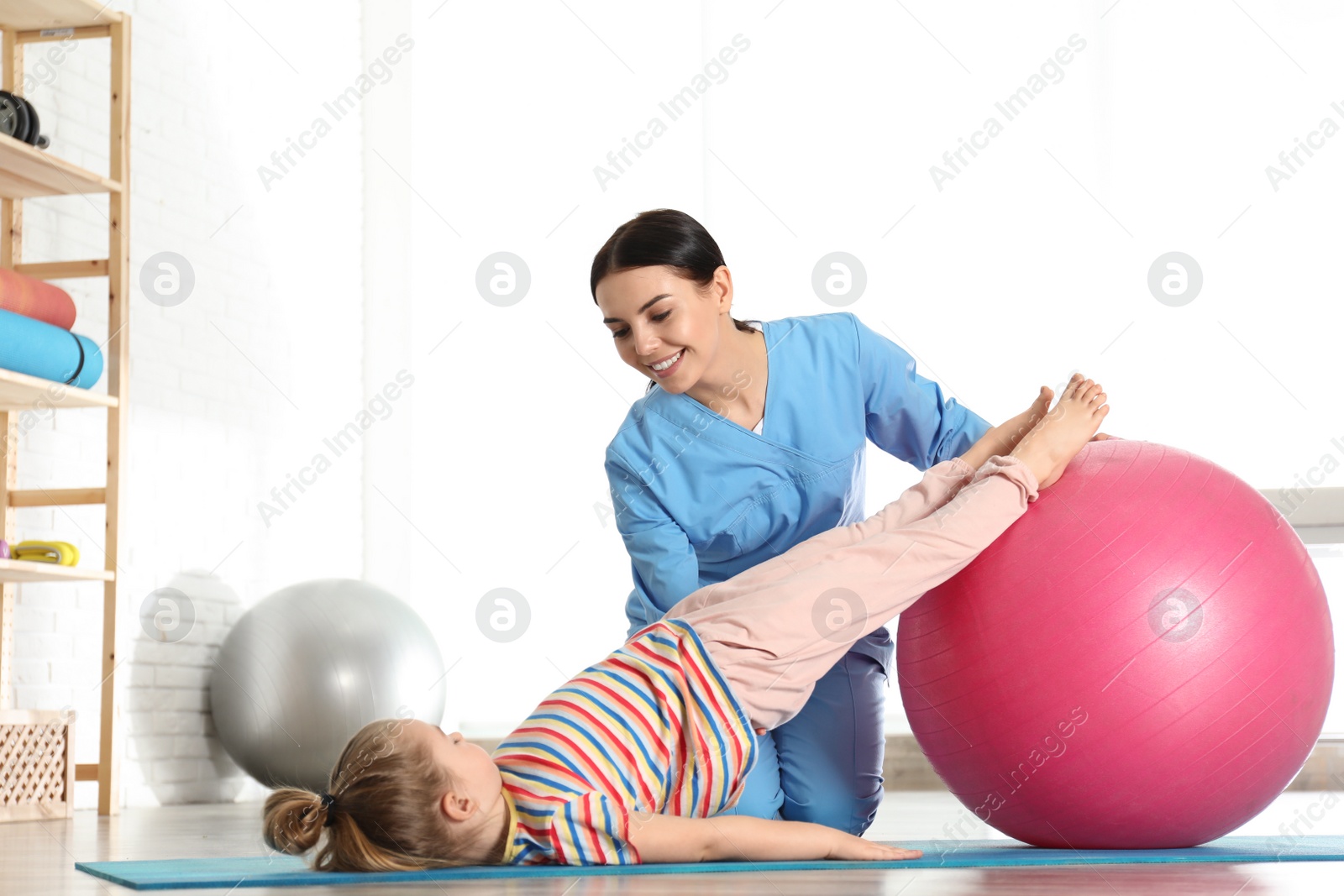 Photo of Orthopedist working with little girl in hospital gym