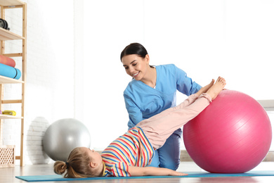 Orthopedist working with little girl in hospital gym