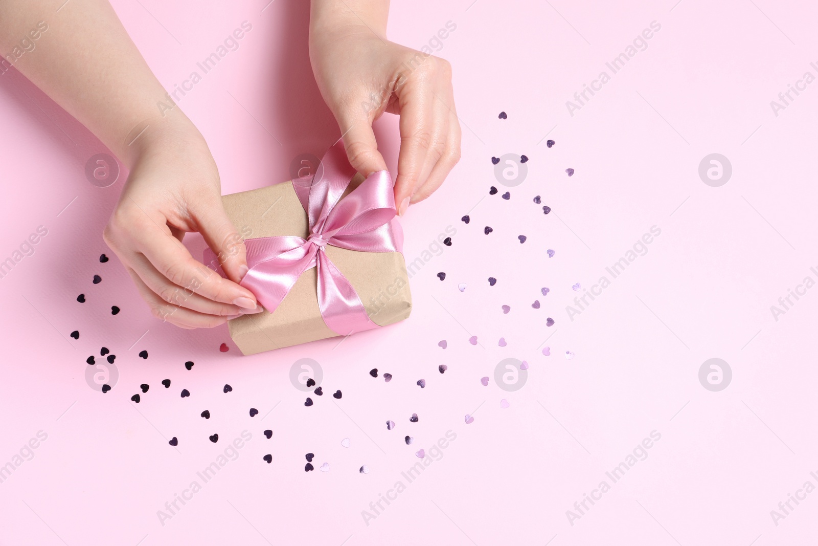 Photo of Woman with gift box and confetti on pink background, above view. Space for text