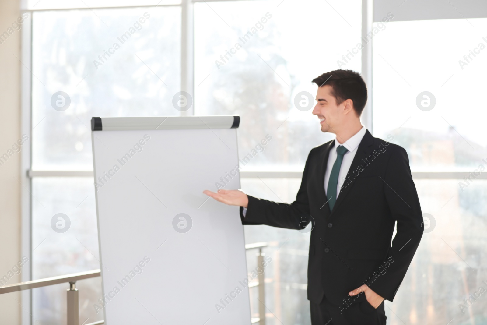 Photo of Business trainer giving presentation on flip chart board indoors