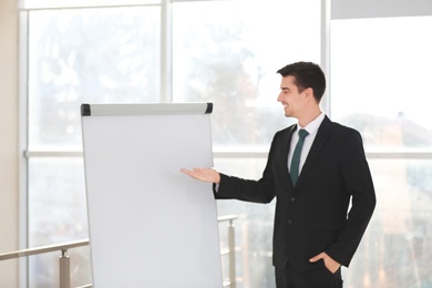 Business trainer giving presentation on flip chart board indoors