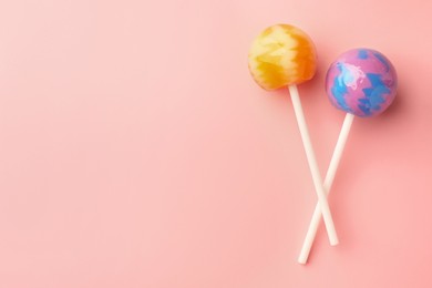 Photo of Tasty lollipops on pink background, flat lay. Space for text