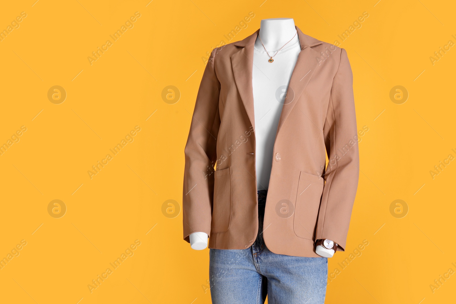 Photo of Female mannequin dressed in white t-shirt with necklace, stylish jacket and jeans on orange background, space for text