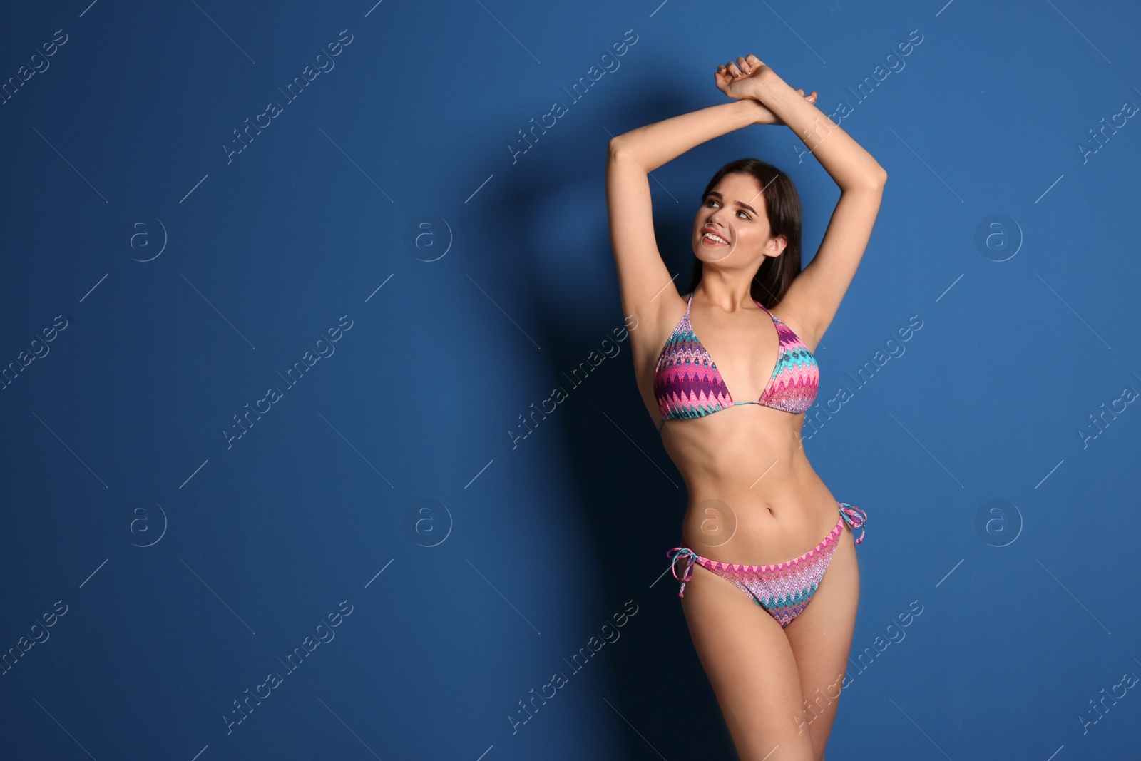 Photo of Beautiful young woman wearing bikini on blue background. Space for text