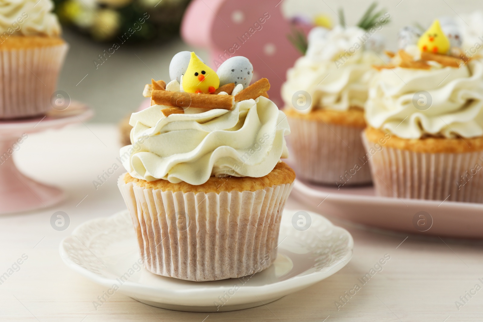 Photo of Tasty Easter cupcakes with vanilla cream on light wooden table