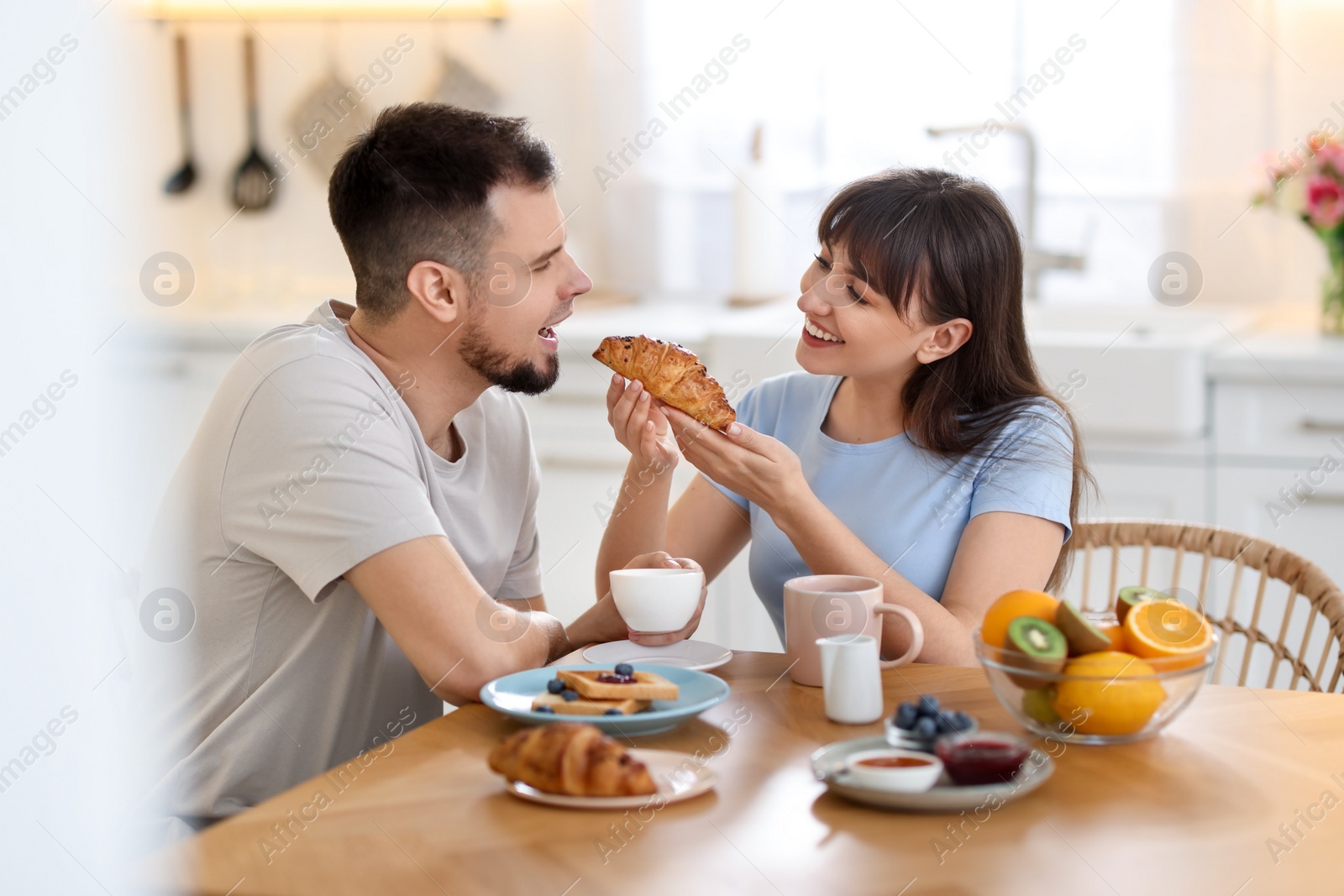 Photo of Tasty breakfast. Happy wife feeding her husband at home
