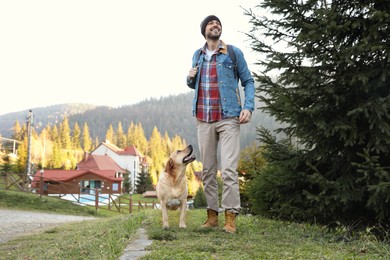 Happy man and adorable dog in mountains. Traveling with pet