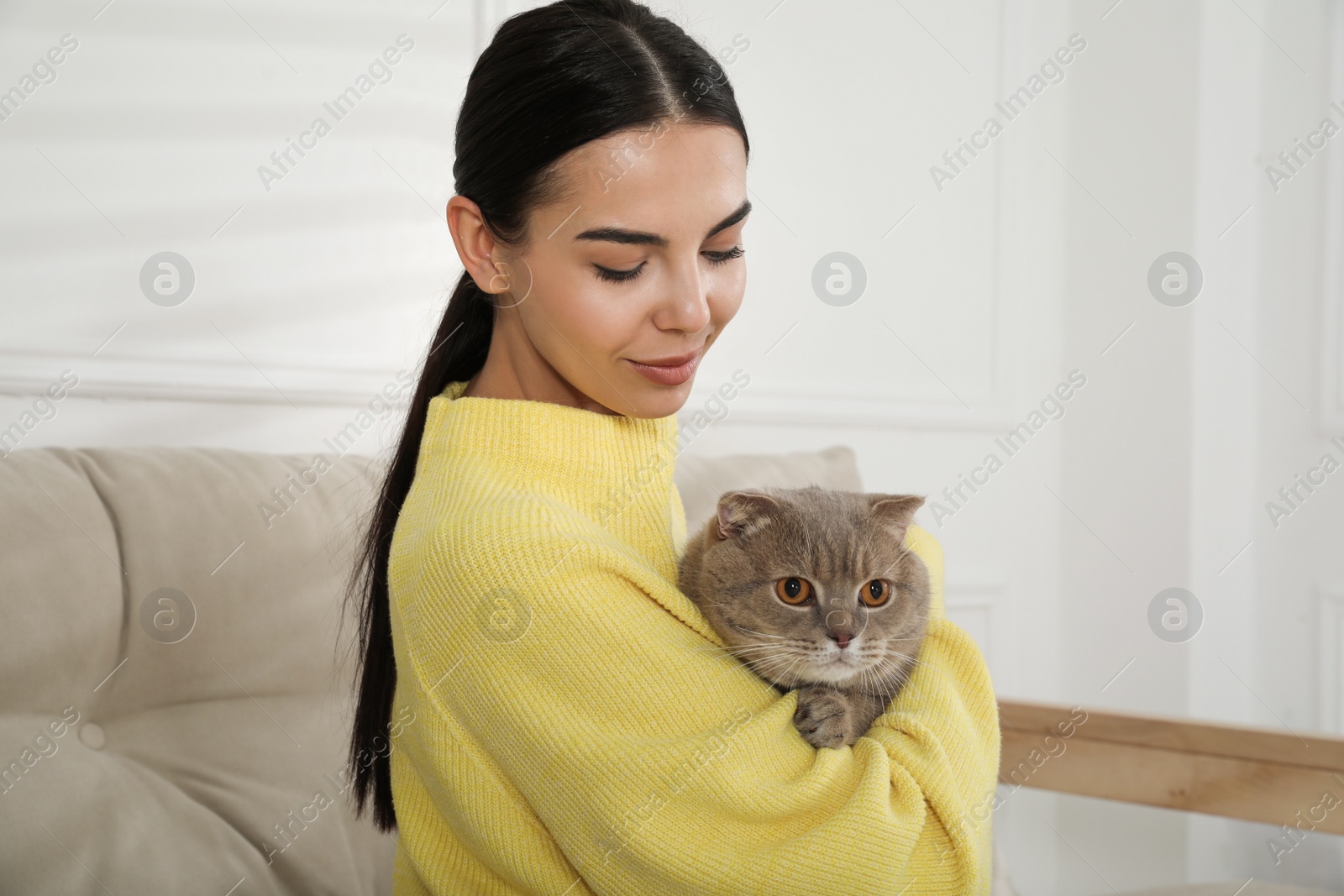 Photo of Woman with her adorable cat on sofa at home