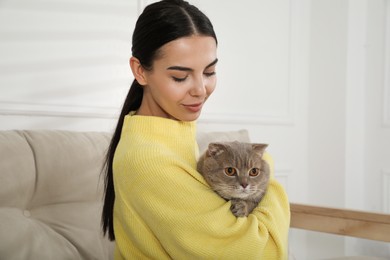 Woman with her adorable cat on sofa at home