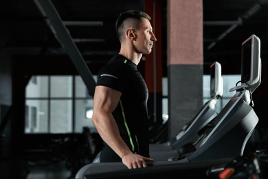 Photo of Man working out on treadmill in modern gym