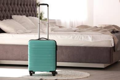 Photo of Colorful suitcase packed for journey in bedroom. Space for text