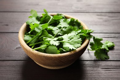 Photo of Fresh aromatic cilantro in bowl on wooden table