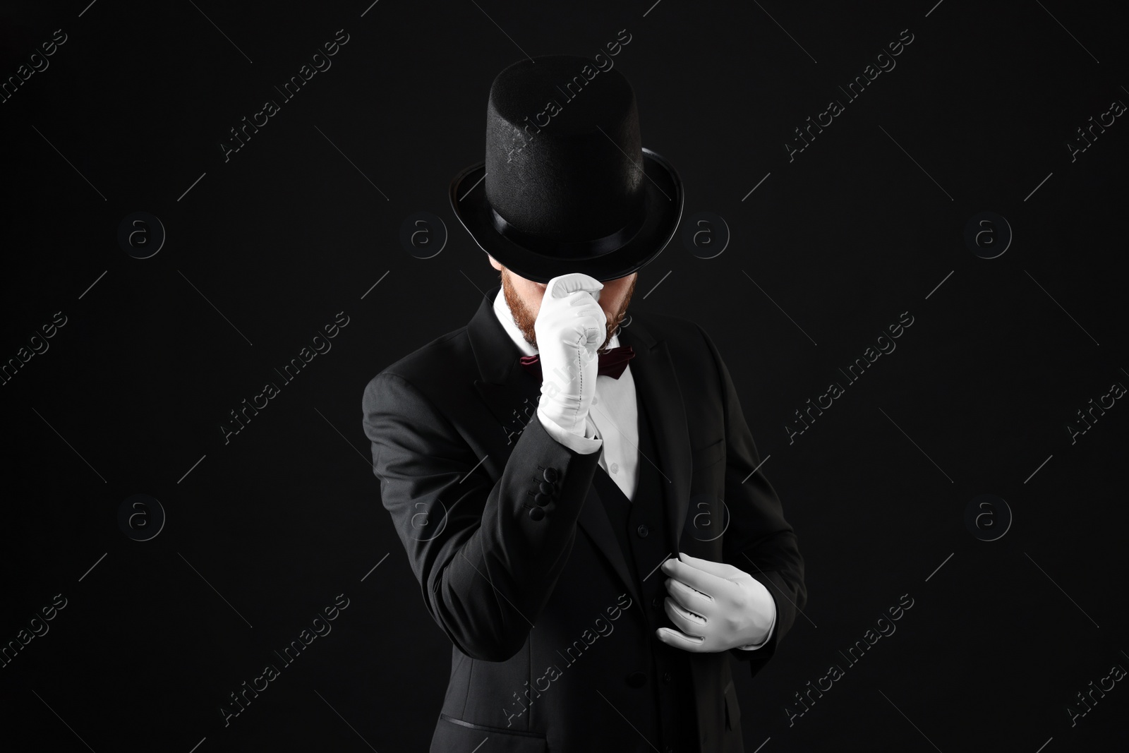 Photo of Magician in top hat on black background