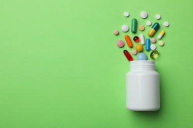 Photo of Bottle with different pills on color background, flat lay. Space for text