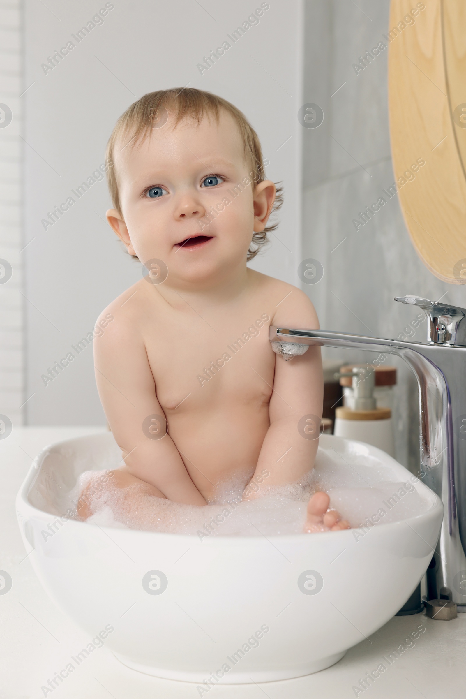 Photo of Cute little baby bathing in sink at home