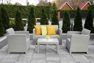 Photo of Beautiful rattan garden furniture, soft pillows and yellow chrysanthemum flowers in backyard