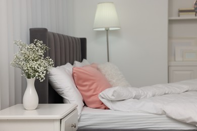 Photo of Stylish bedroom interior with comfortable bed, nightstand and lamp