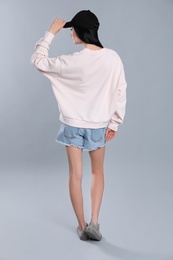 Photo of Young woman in sweater on grey background. Mock up for design