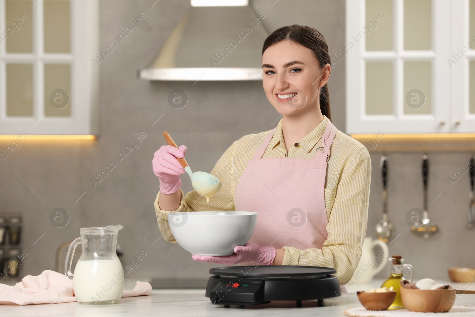 Photo of Young woman cooking delicious crepes in kitchen. Space for text