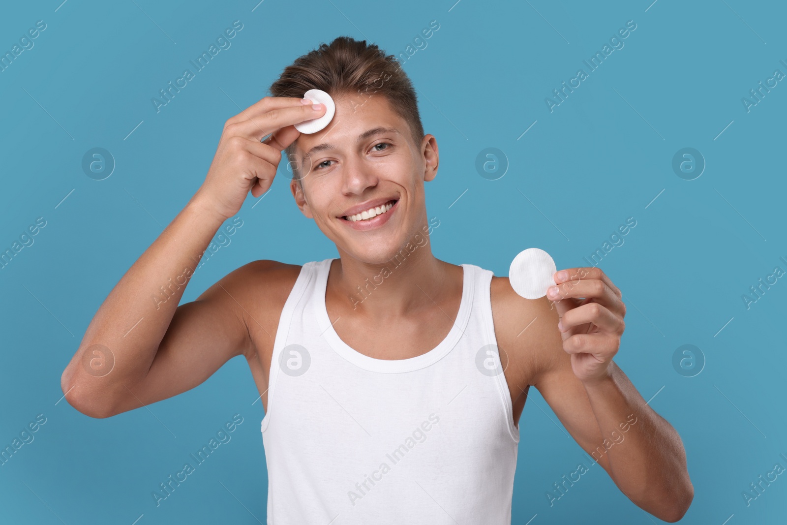 Photo of Handsome man with cotton pads on light blue background