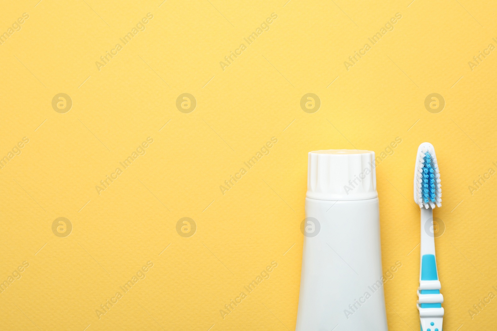 Photo of Blank tube of toothpaste and brush on color background, top view with space for text