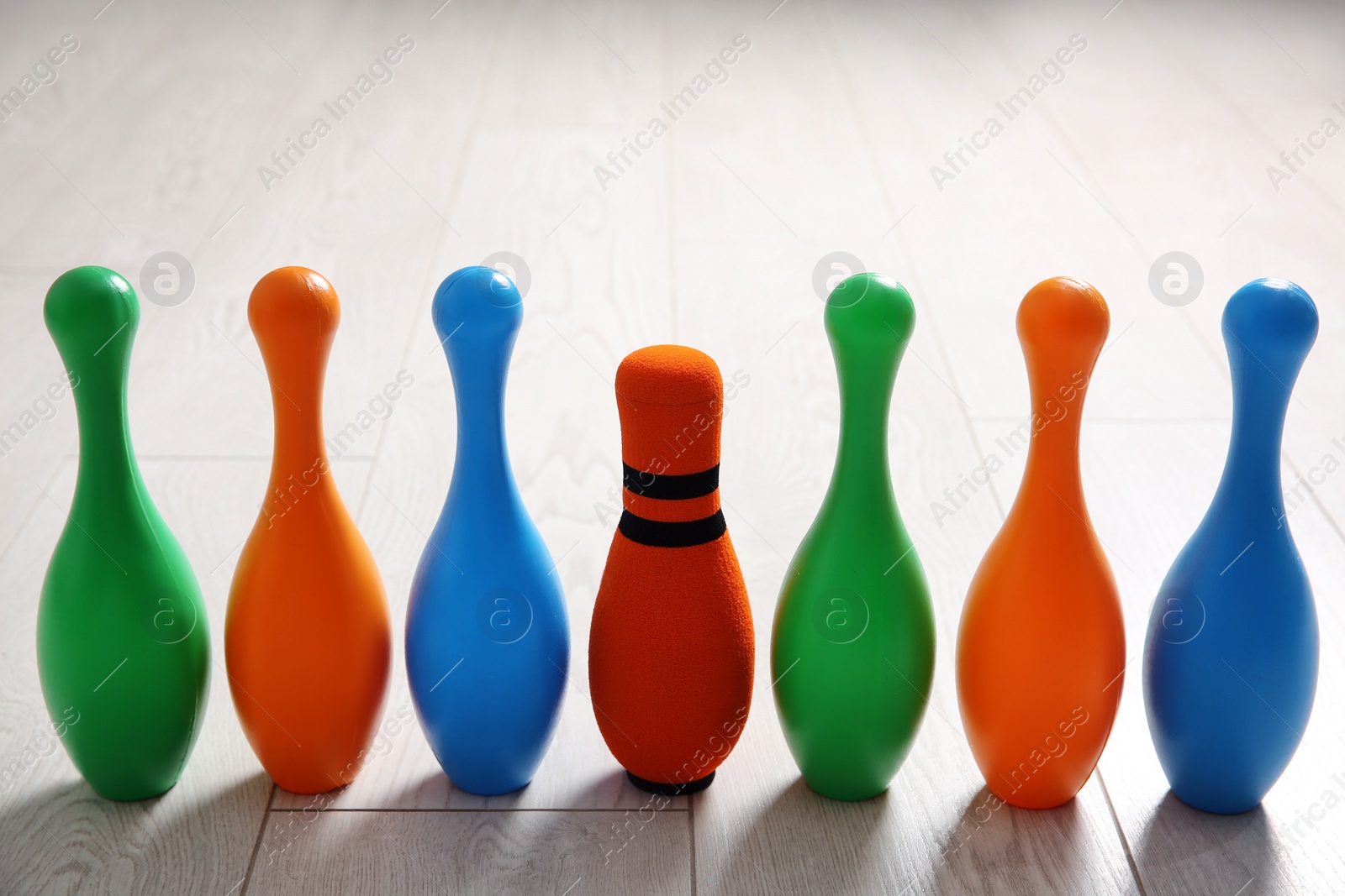 Photo of Fabric bowling pin among others on wooden floor. Diversity concept