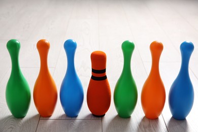 Fabric bowling pin among others on wooden floor. Diversity concept
