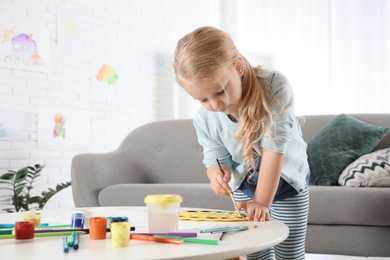 Photo of Cute little child painting at table indoors