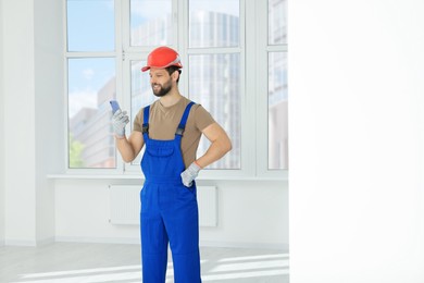 Photo of Professional repairman in uniform with phone indoors