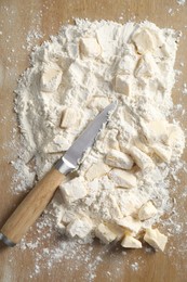 Photo of Making shortcrust pastry. Flour, butter and knife on wooden table, top view