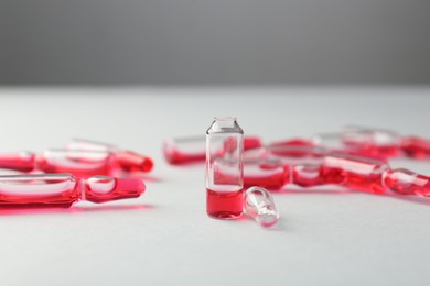 Photo of Glass ampoules with liquid on white background, closeup