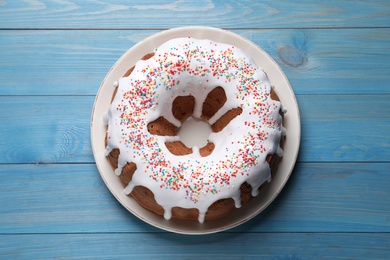 Photo of Glazed Easter cake with sprinkles on blue wooden table, top view