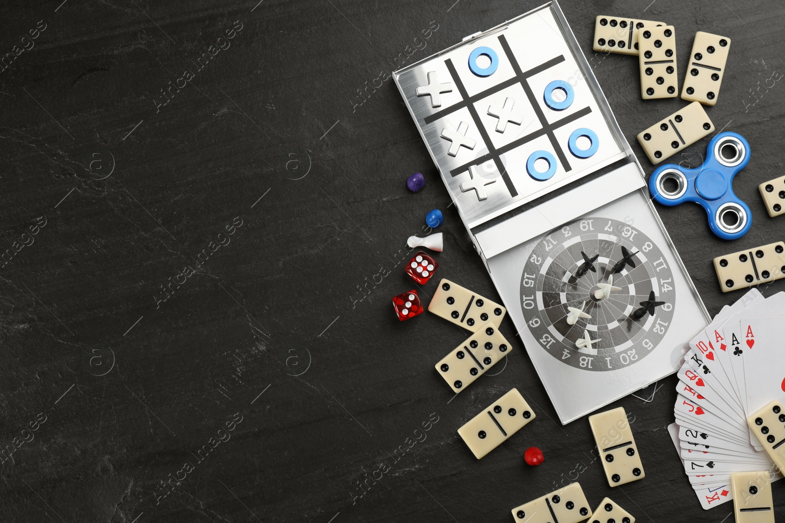 Photo of Elements of different board games on black slate table, flat lay. Space for text