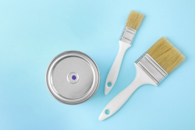 Photo of Flat lay composition with can of paint and brushes on color background