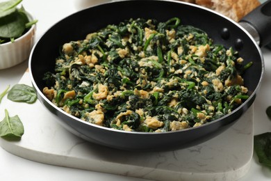 Photo of Tasty spinach dip with eggs in dish served on white table, closeup