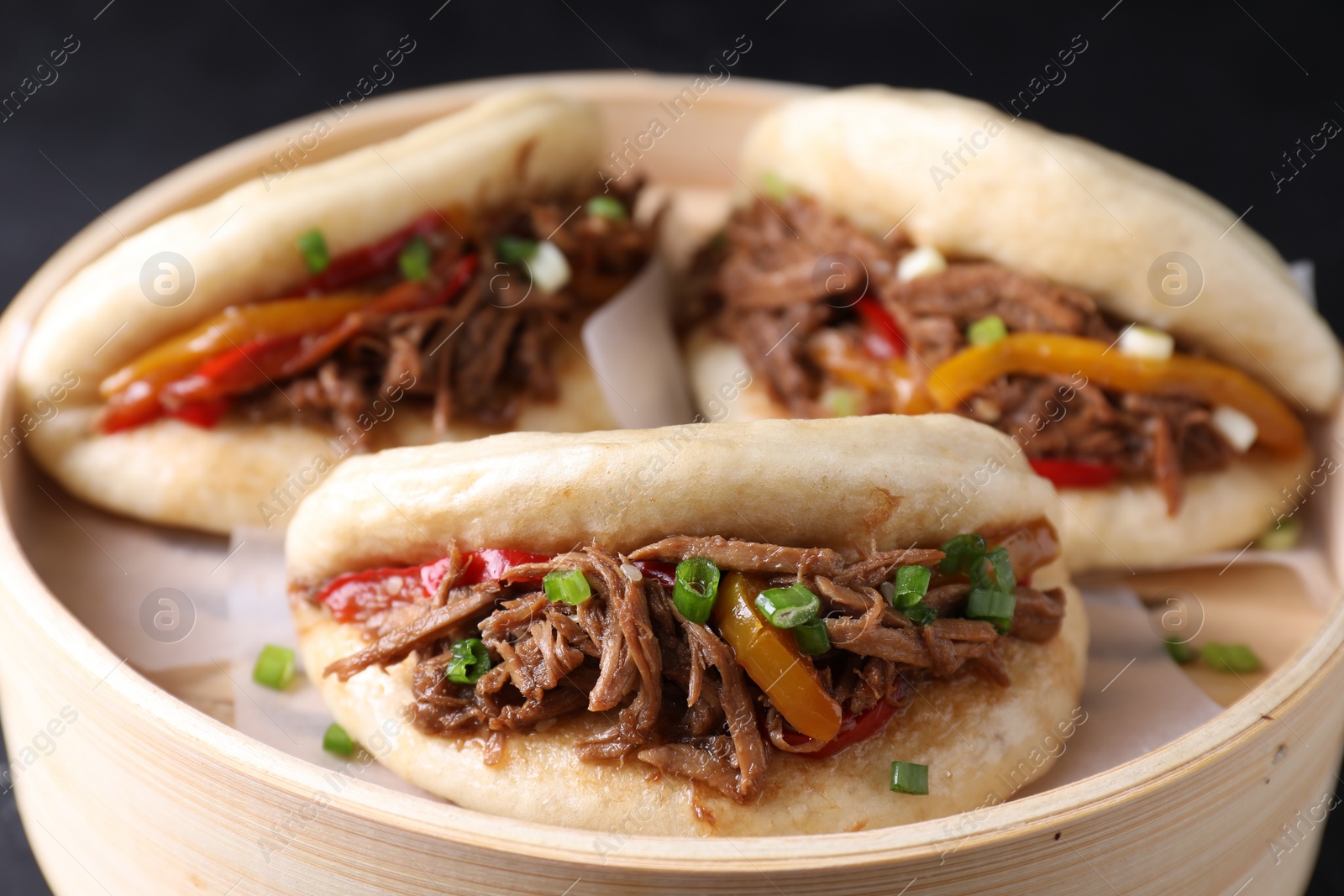 Photo of Delicious gua bao in bamboo steamer on table, closeup