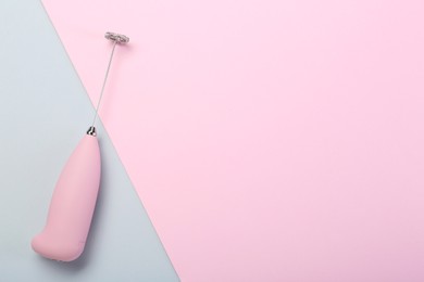 Pink milk frother wand on color background, top view. Space for text