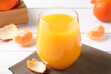 Glass of fresh tangerine juice on table