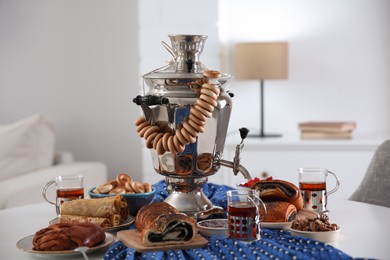 Photo of Traditional Russian samovar with treats on white table at home