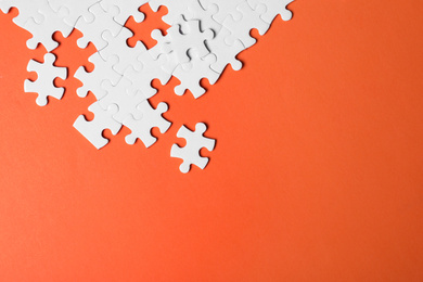 Photo of Blank white puzzle pieces on orange background, flat lay. Space for text
