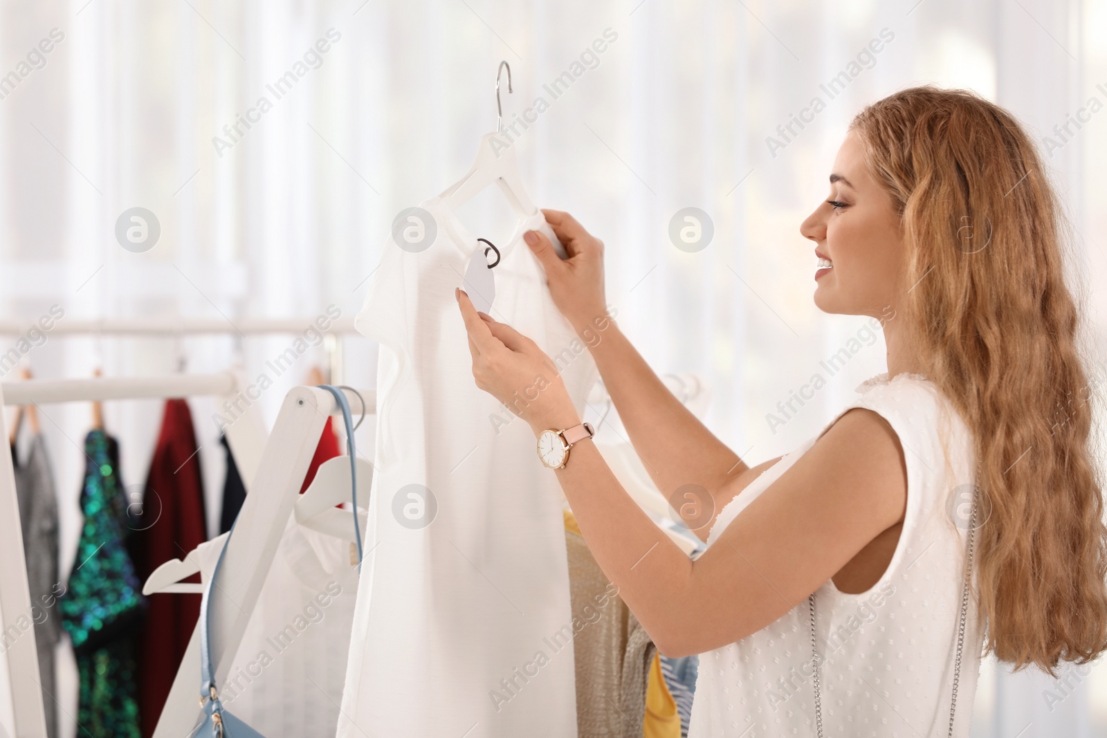 Photo of Young woman choosing stylish clothes in boutique