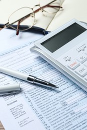 Photo of Calculator, glasses, documents and stationery on table, closeup. Tax accounting