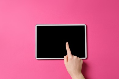 Online store. Woman using tablet on pink background, top view