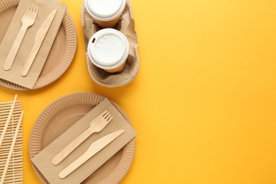 Photo of Flat lay of paper and wooden tableware on yellow background, space for text. Eco friendly lifestyle