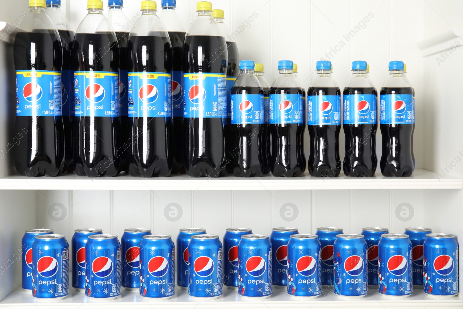 Photo of MYKOLAIV, UKRAINE - FEBRUARY 10, 2021: Cans and bottles of Pepsi on white shelves