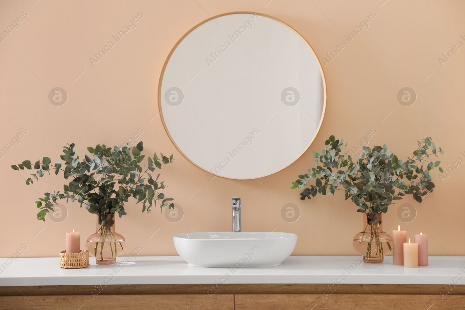 Photo of Stylish mirror, eucalyptus branches and vessel sink in modern bathroom. Interior design