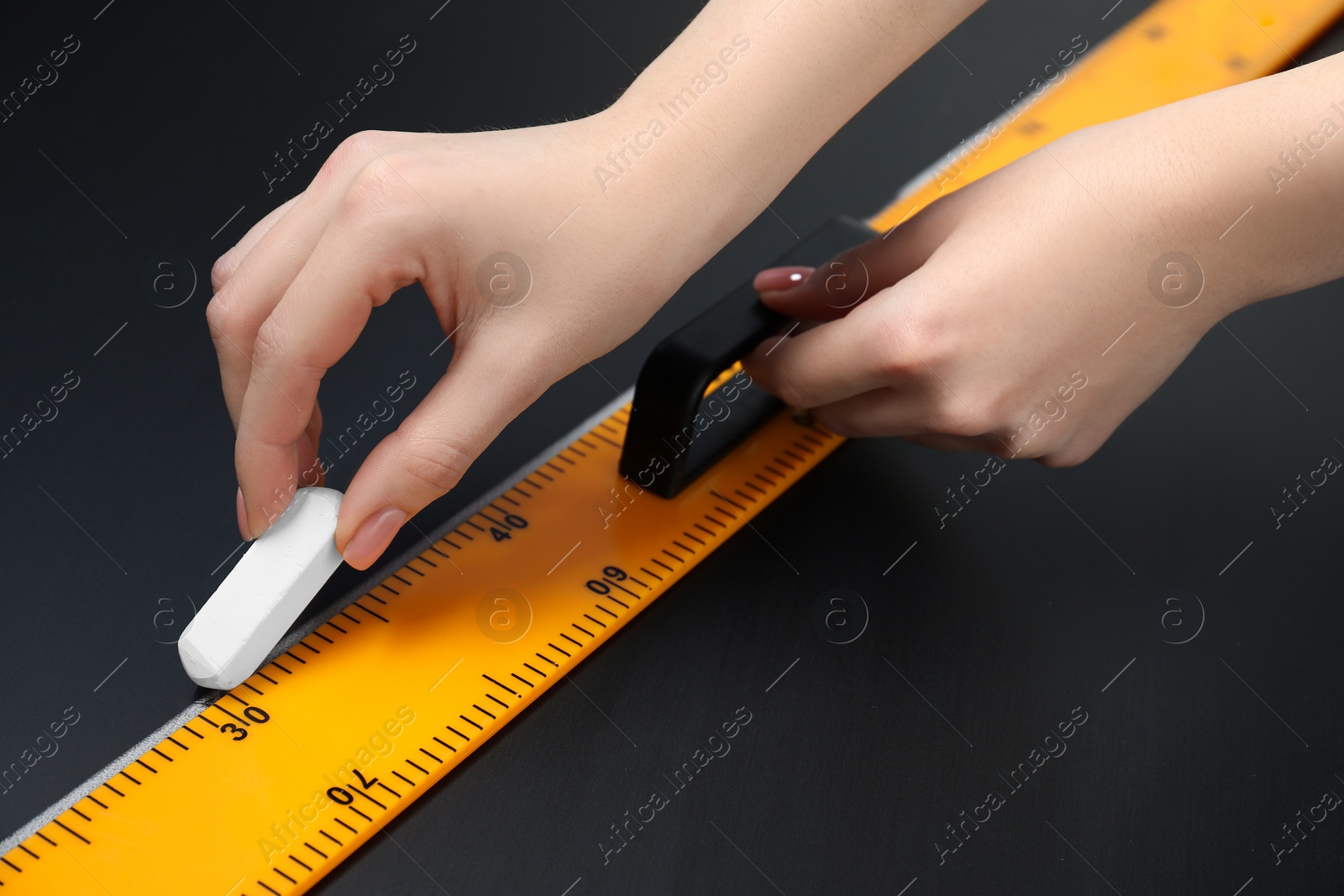 Photo of Woman drawing with chalk and ruler on blackboard, closeup