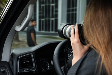 Private detective with camera spying from car, closeup