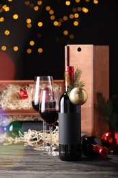 Bottles of wine, glasses, wooden boxes, fir twigs and Christmas balls on table